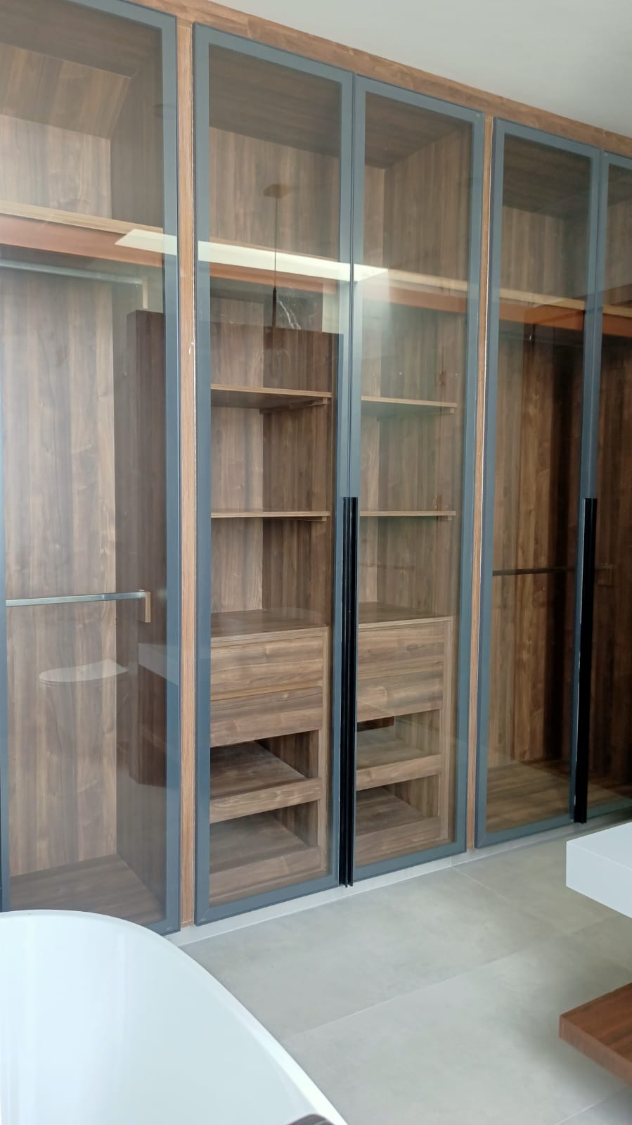Floor-to-ceiling glass wardrobe with walnut interiors