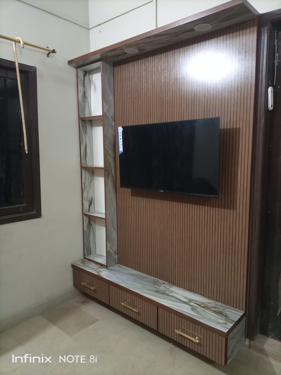 Custom TV wall unit with wood slats and marble shelves